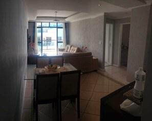 Un salon avec un canapé, une table à manger et des chaises, ainsi qu’une grande fenêtre.