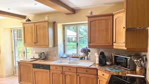 A kitchen with wooden cabinets, a dishwasher, a sink, a coffee maker, and a microwave. - Delightful House for Up to 6 Guests + Baby With Large Secluded Garden Area  (Fleury)