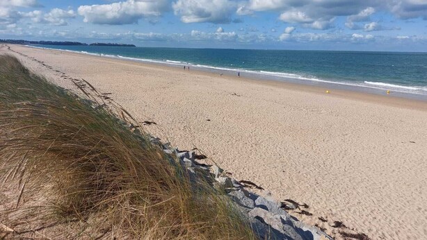 A wide sandy beach with gentle waves, a clear sky, and a distant shoreline. - Delightful House for Up to 6 Guests + Baby With Large Secluded Garden Area  (Fleury)