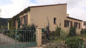 Un edificio a due piani con facciata in pietra, un numero 112 e un cancello con decorazioni.