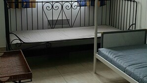 Una camera del dormitorio con un letto a castello, un tavolino e una finestra con tende a motivi.