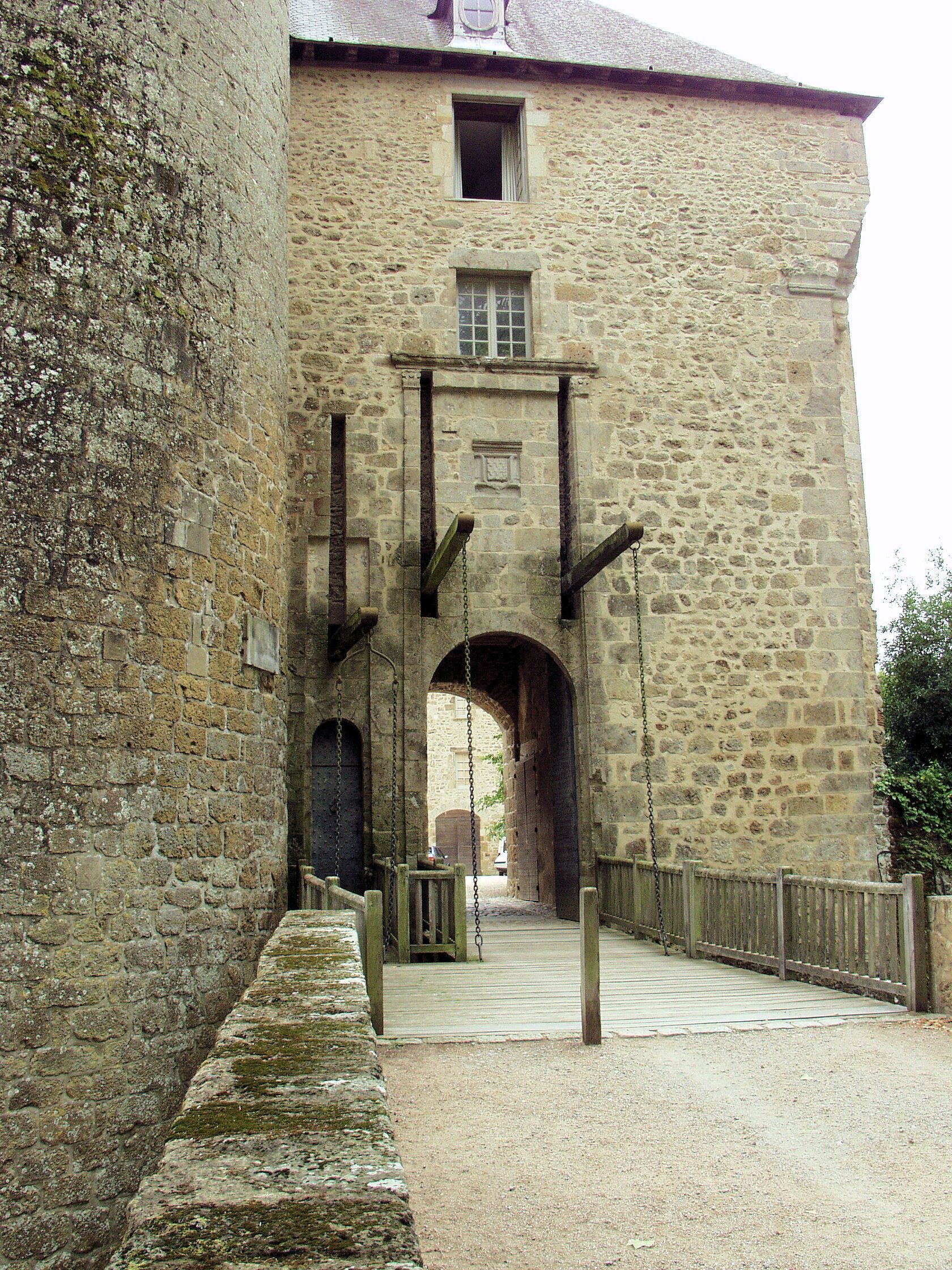 A stone building with a large arched entrance and a wooden fence.
