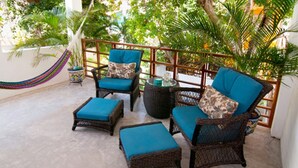 Ein Patio mit Korbmöbeln, darunter zwei Stühle und zwei Poufs, alle mit blauen Kissen.