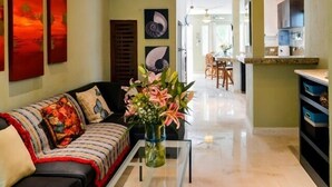 Ein Wohnzimmer mit einer Couch, einem Couchtisch mit Blumenvase und Kunstwerken an den Wänden.