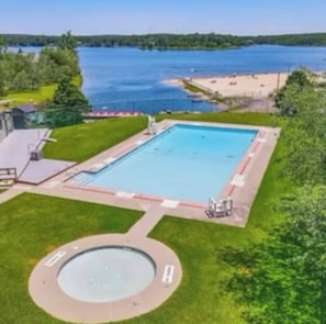 A swimming pool with a circular hot tub, surrounded by a grassy area and a beach. - Perfect Getaway In The Poconos! (House #2) HotTub !! Gameroom !! WiFi !! (Albrightsville)