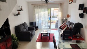 Un salon comprenant un canapé, une table basse, un téléviseur et un coin repas avec une table et des chaises.