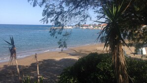 A beach with a clear view of the sea, a sandy shore, and some buildings in the background. - Villa Dora · Villa Dora (Faliraki)