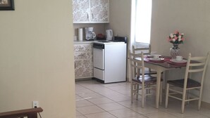 A room with a bed, a dining table with chairs, a kitchen area with a refrigerator, and a window. - Cottage within walking distance to Casey Key Beach (Nokomis)