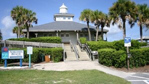 A building with a dome and a staircase leading to the entrance, surrounded by palm trees and a sign indicating 'Nokomis Beach'. - Cottage within walking distance to Casey Key Beach (Nokomis)