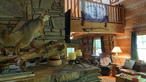 Ein rustikales Lodge-Interieur mit Kamin aus Stein, einer Känguru-Skulptur und einem Banner mit der Aufschrift "Highlands N. 1875".