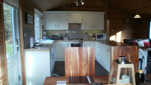 Interior de una cabaña de madera con cocina, comedor y una pequeña sala de estar.