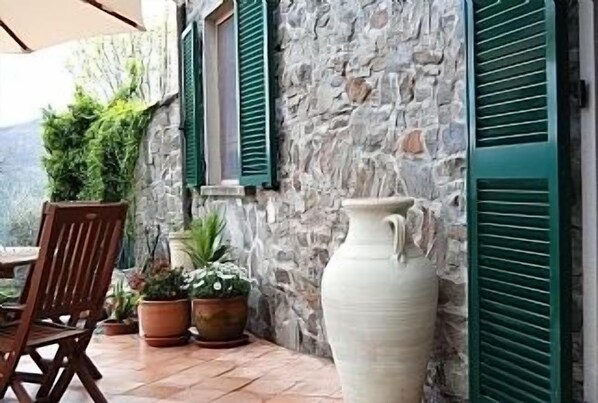 Relax in a serene patio surrounded by lush greenery and a charming stone wall.