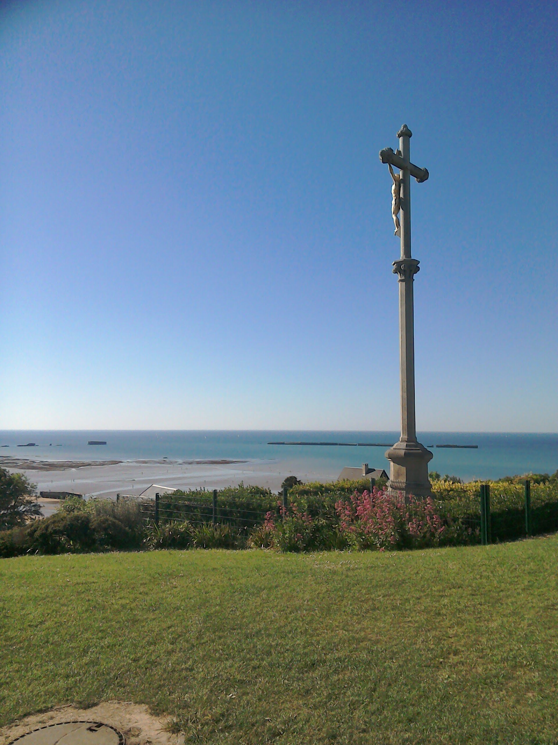 A coastal view with a monument in the foreground and the sea in the background.