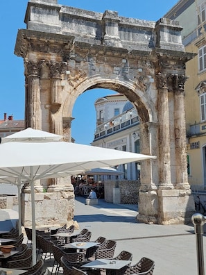 Sit beneath the shade of a large umbrella and take in the historic views of an ancient stone archway.