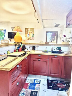 Une cuisine compacte avec un plan de travail en bois, une machine à café et un meuble rouge.