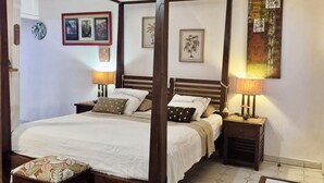 Una cama con dosel de madera, una mesita de noche con lámpara y un tapete en el suelo.