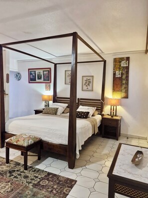 A four-poster bed with a wooden frame, a bedside table with a lamp, and a rug on the floor.