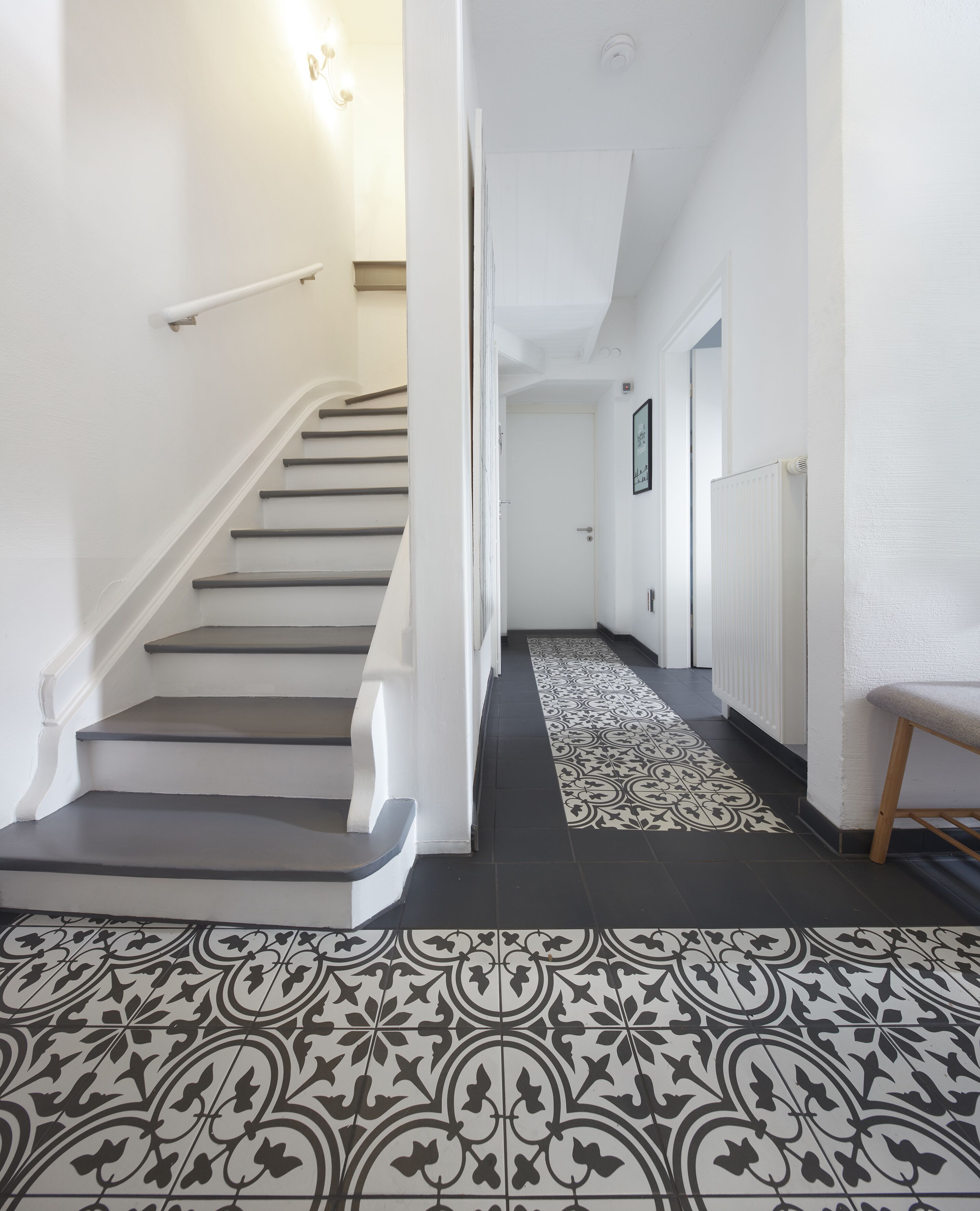 A staircase with a patterned floor leading to a door.