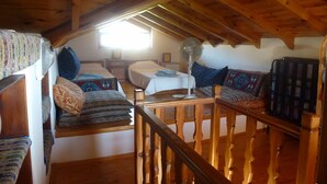Een gezellig slaapkamer op zolder met een houten plafond, een bed met beddengoed met een patroon, een ventilator en een raam dat voor natuurlijk licht zorgt.