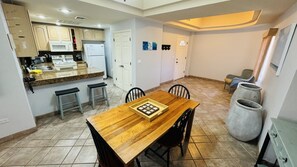 A compact kitchen with a wooden dining table, two bar stools, and a refrigerator.
