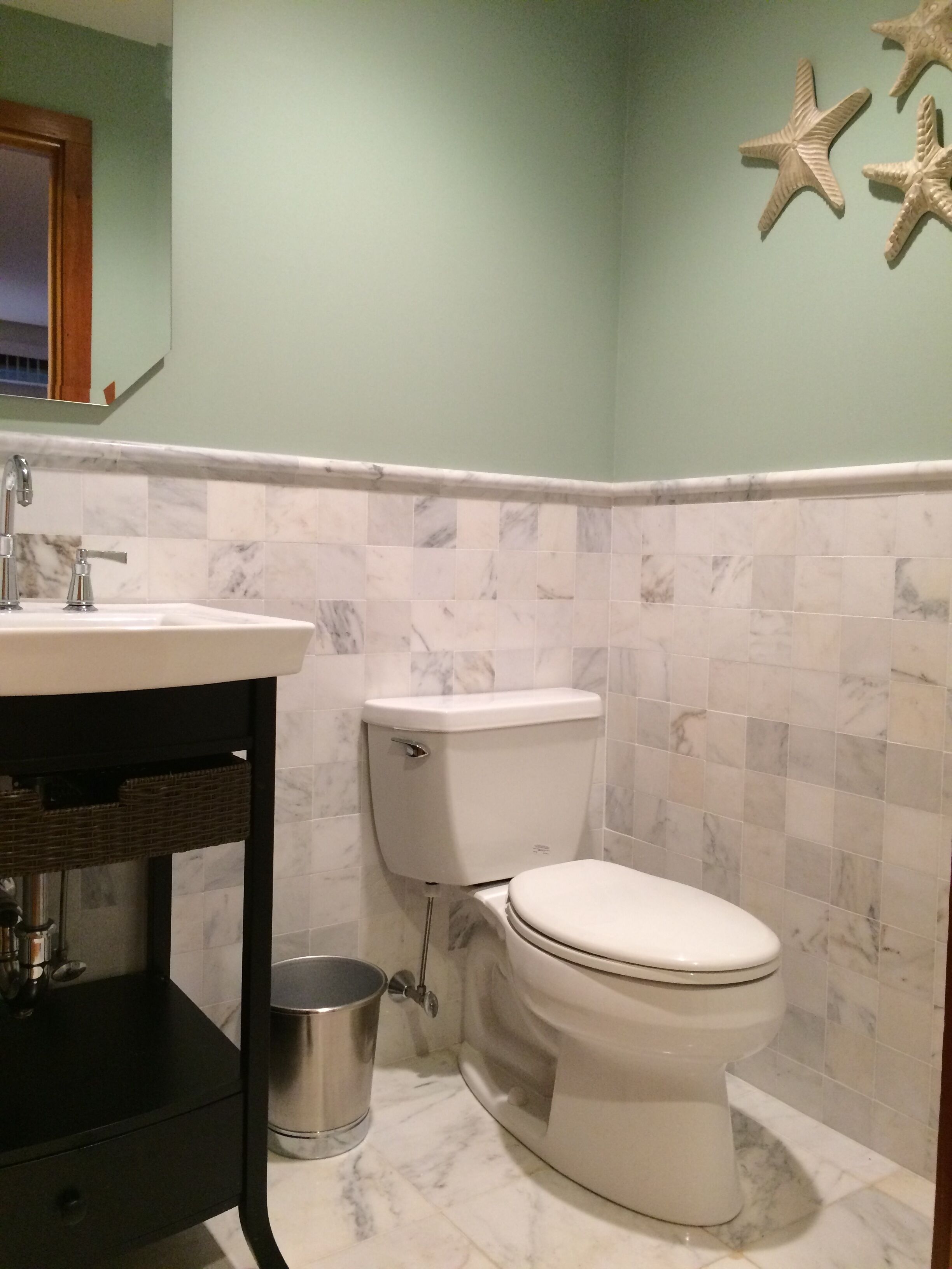 Une salle de bain avec des toilettes, un lavabo et une étoile de mer décorative accrochée au mur.