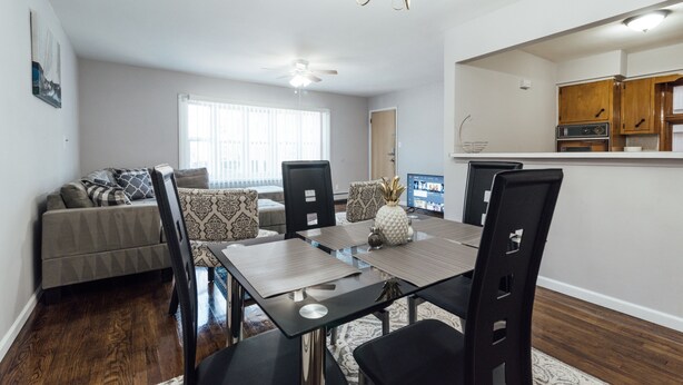 A dining area with a table set for four, surrounded by chairs, a ceiling fan, and a chandelier.