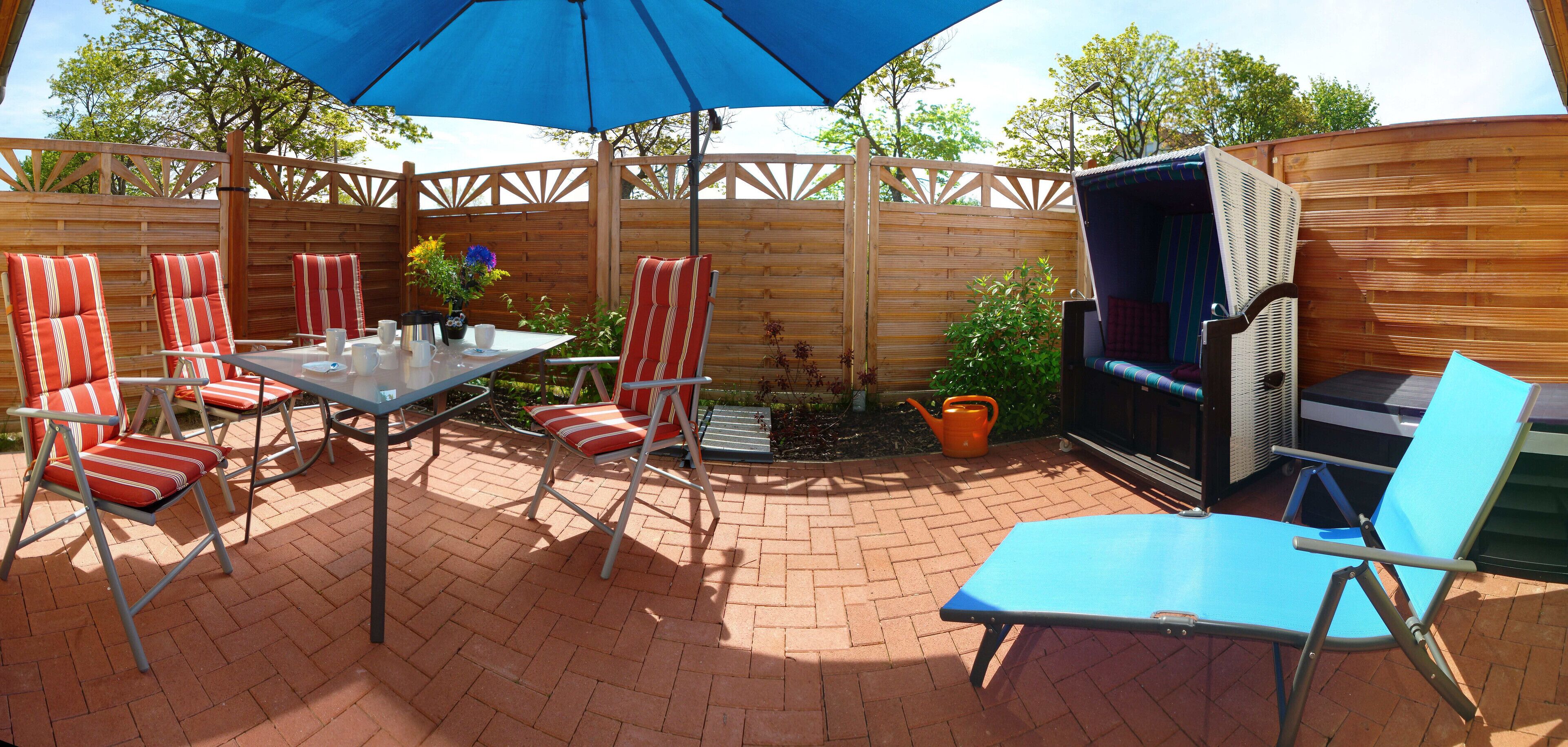 An outdoor patio with a table, chairs, and a blue umbrella.