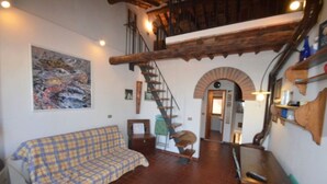 A room with a checkered sofa, a staircase, and a rustic wooden ceiling. - Il Rifugio - Capoliveri  - IL RIFUGIO (Capoliveri)
