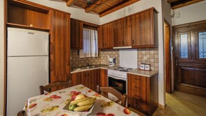 Une cuisine avec des meubles de rangement en bois, un réfrigérateur, une cuisinière et une table à manger sur laquelle on a disposé des fruits.