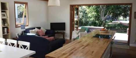 A cozy living area with a wooden dining table, a sofa, and a television.