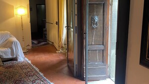A room with a bed covered in white, a patterned rug, a wooden ceiling, and a door leading outside. - Authentic Tuscan Villa with Pool and Panoramic Views near Vinci – Tuscany (lamporecchio)