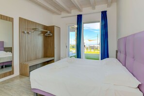 Ein Schlafzimmer mit Bett, Kleiderschrank, Bank und Blick ins Freie.
