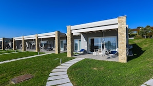 A modern hotel with a covered outdoor seating area, stone pillars, and a clear sky. - Relais Rosa dei Venti: 1 bedroom elegance, 2 pools, lake view! (Moniga del Garda)
