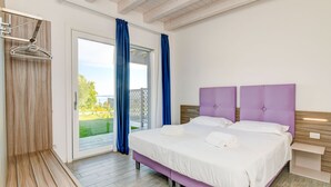 A bedroom with a bed, a wooden bench, and a view of the outdoors. - Relais Rosa dei Venti: 1 bedroom elegance, 2 pools, lake view! (Moniga del Garda)