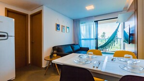 Camera d'albergo moderna con angolo ristoro, divano e ampia finestra vista su spazi verdi.
