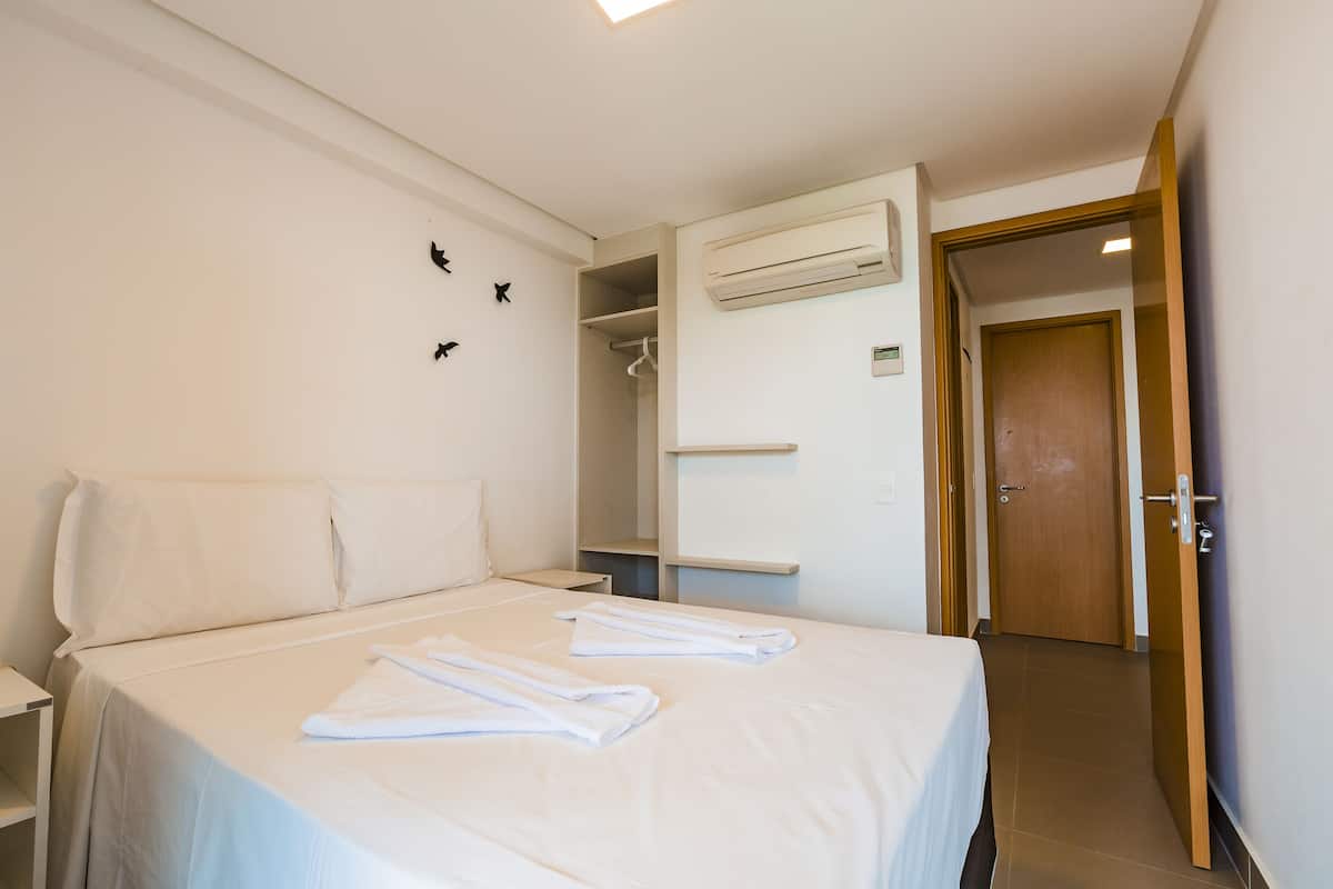 Une chambre d’hôtel comprenant un lit, une table de chevet, un appareil de climatisation, une armoire et une porte.