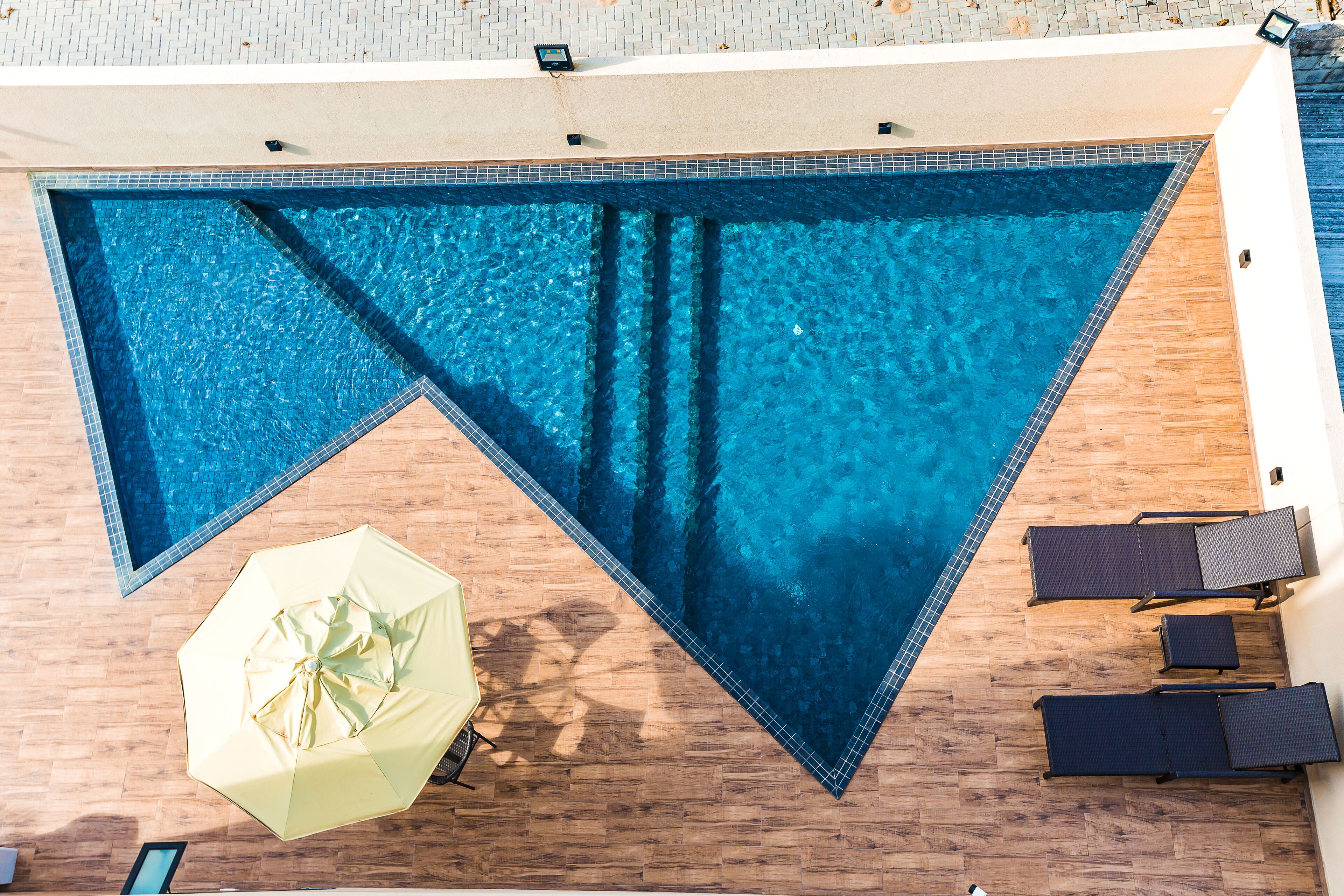 Una piscina al aire libre, sombrillas, sillones reclinables de piscina