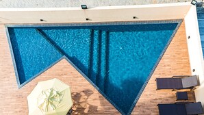 Una piscina sul tetto con un pontile in legno, un ombrellone giallo e due poltrone da relax.