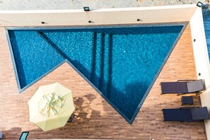 Una piscina al aire libre, sombrillas, sillones reclinables de piscina