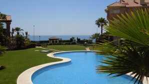 A swimming pool with a curved edge, surrounded by well-maintained grass and palm trees. - Fantastic penthouse of 140m2 (Torrox)