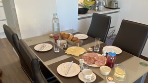 A dining table set with plates, cutlery, and condiments, surrounded by chairs.