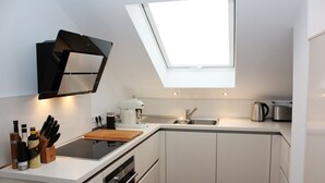 A modern kitchen with a skylight, white cabinets, and a coffee maker.
