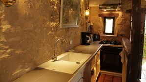 Une cuisine rustique avec un évier blanc, une cuisinière et une petite fenêtre.