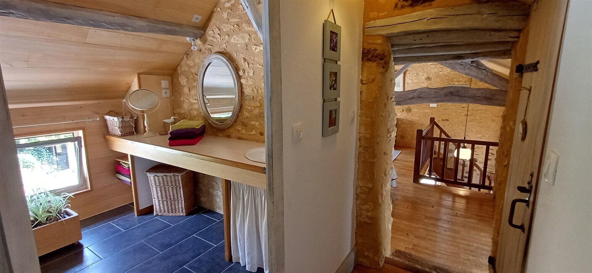 A rustic bathroom with a wooden vanity, a mirror, and a small window.