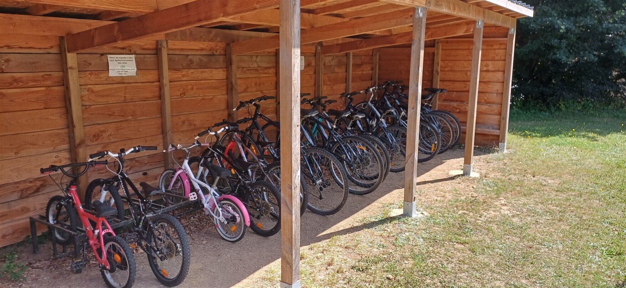 A covered bicycle parking area with multiple bicycles parked under wooden beams.