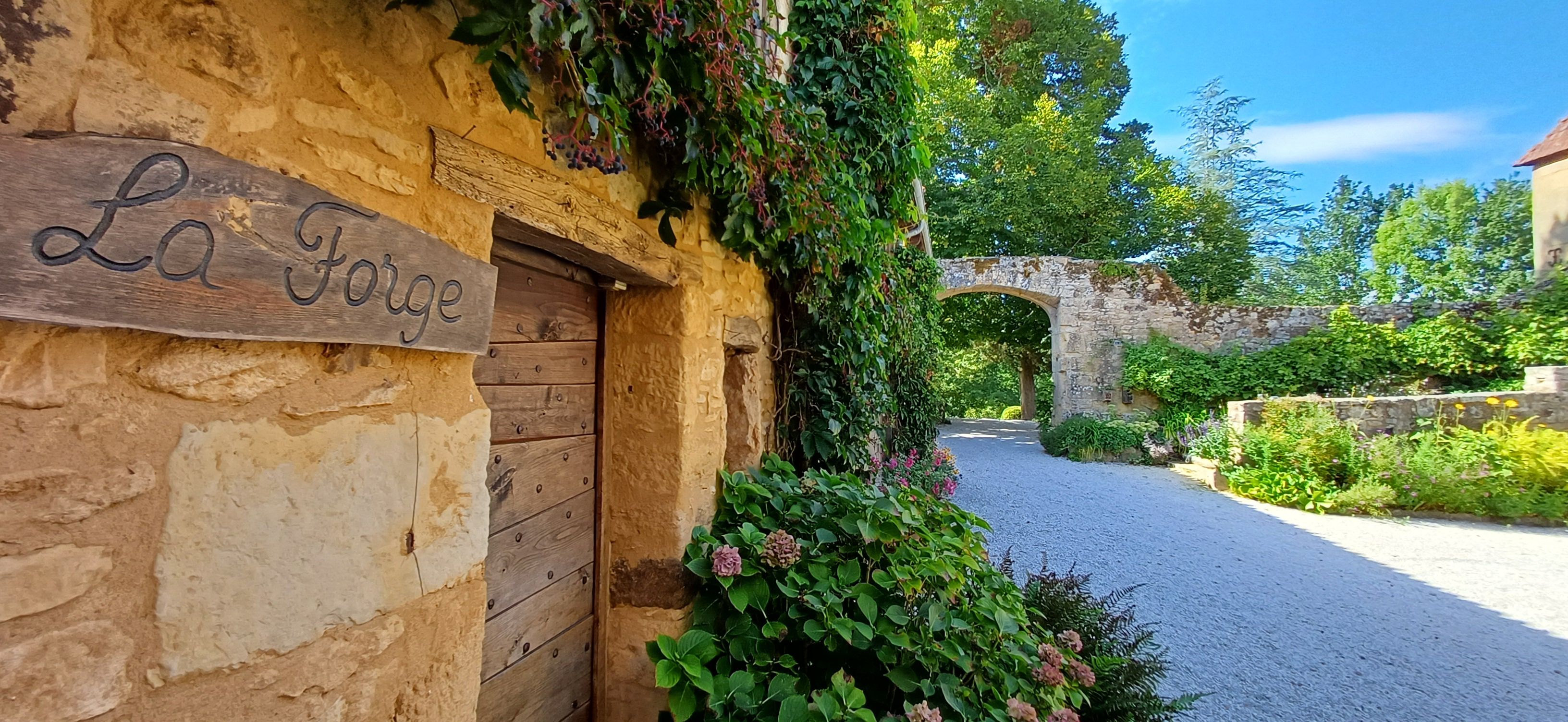 Un edificio rústico de piedra con puerta de madera y un cartel que dice 'La Forge'.