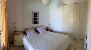 Ein Schlafzimmer mit einem Bett, zwei Nachttischen, einem Schrank und einem an der Wand hängenden Kunstwerk.