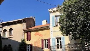Une vue d’une rue avec un café appelé « LA PLACE DE MOUGIN » et des tables en terrasse.