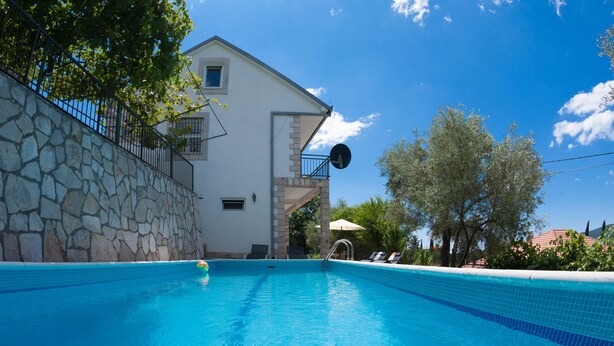 Ein Schwimmbecken mit einer Steinmauer und einem weißen Gebäude im Hintergrund.