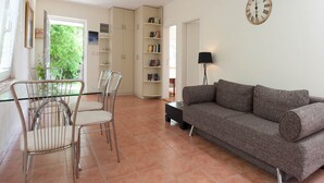 Ein Wohnzimmer mit einer Couch, Sesseln, einem Bücherregal und einer Wanduhr.